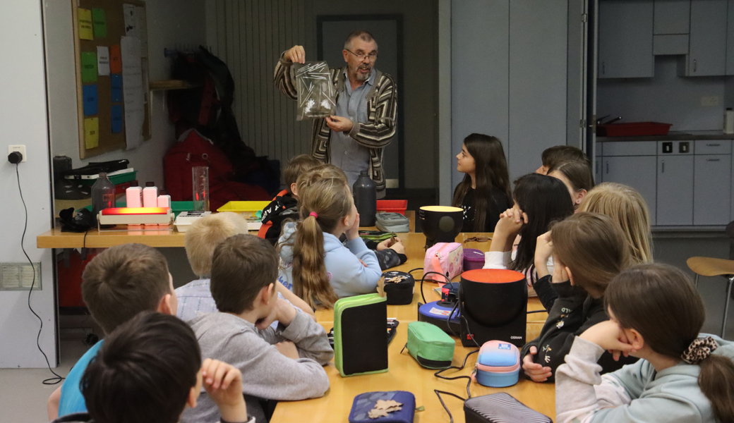 Fotograf Sepp Köppel erläutert den Kindern den Entwicklungsprozess eines Negativs.