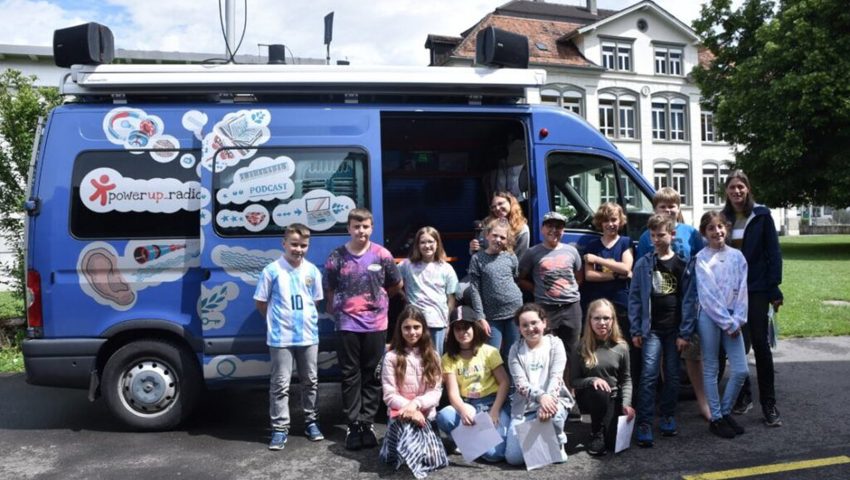  Erinnerungsbild fürs Klassenalbum: Die Schülerinnen und Schüler der 4. Klasse vor dem mobilen Radiostudio, das diese Woche vom Schulhaus Weite aus sendet.