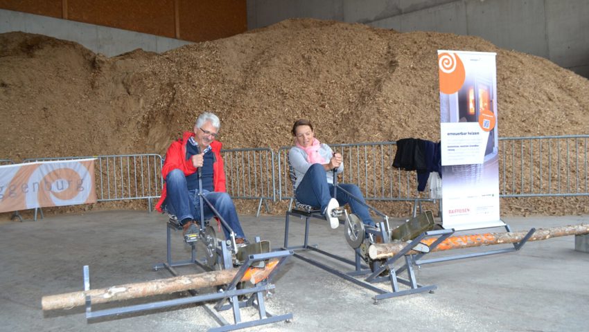  Werner Koller und Doris Sailer strengen sich beim Sägen mit dem Velo an. Im Hintergrund ein Teil des Hackschnitzellagers für die Fernwärmen.