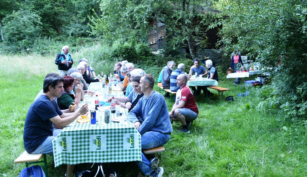 Geselliges Beisammensein: Valcup, im Hintergrund, zwischen Bäumen, das Bienenhaus. 