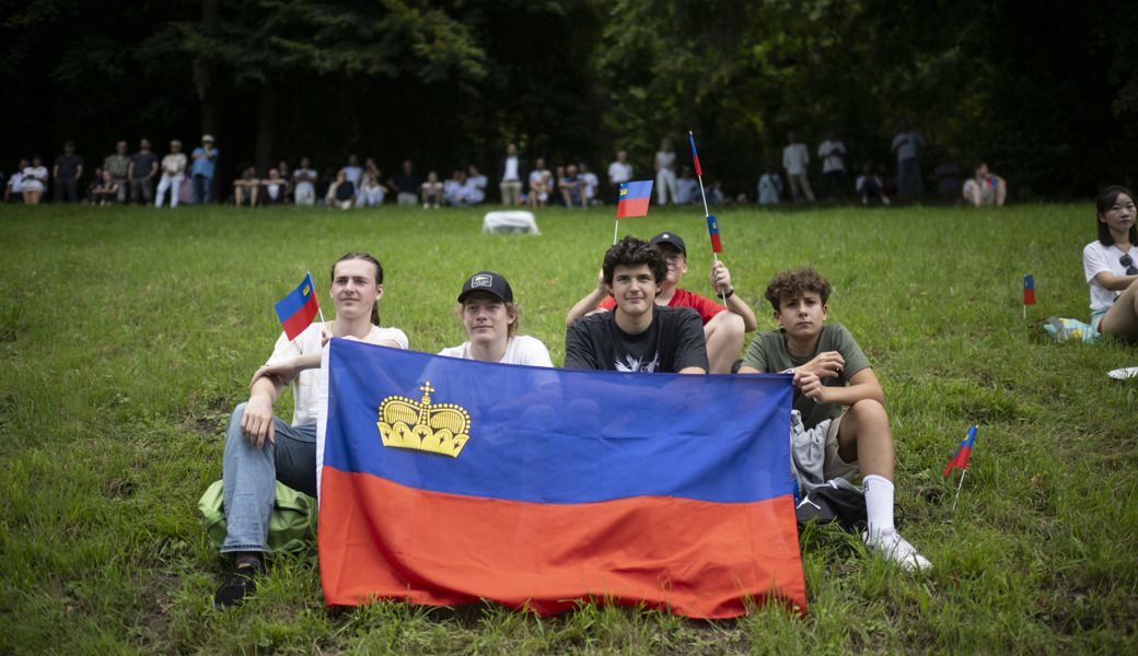 Zaungäste auf der Wiese vor dem Schloss Vaduz: Junge Liechtensteiner mit der Landesflagge.