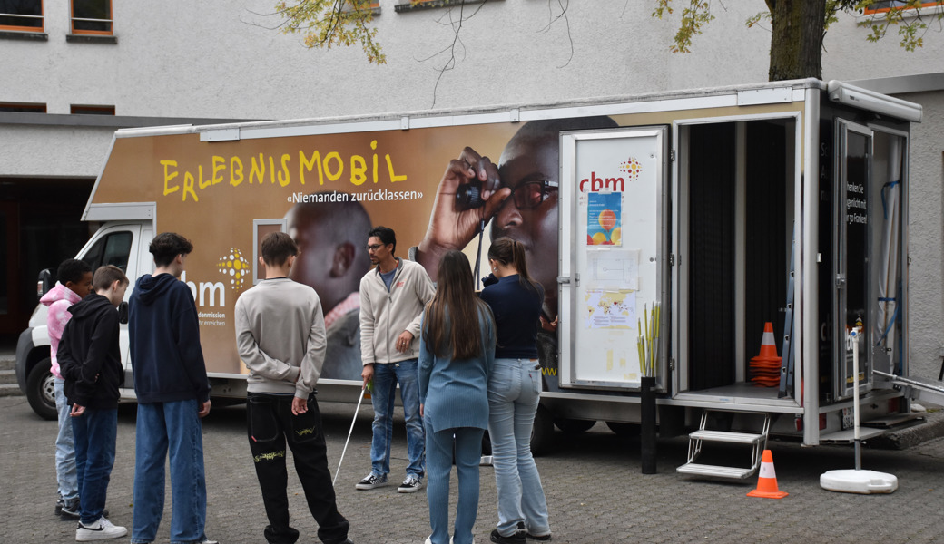 Vor dem Erlebnismobil: Dave Gooljar erklärt den Umgang mit dem Blindenstock.